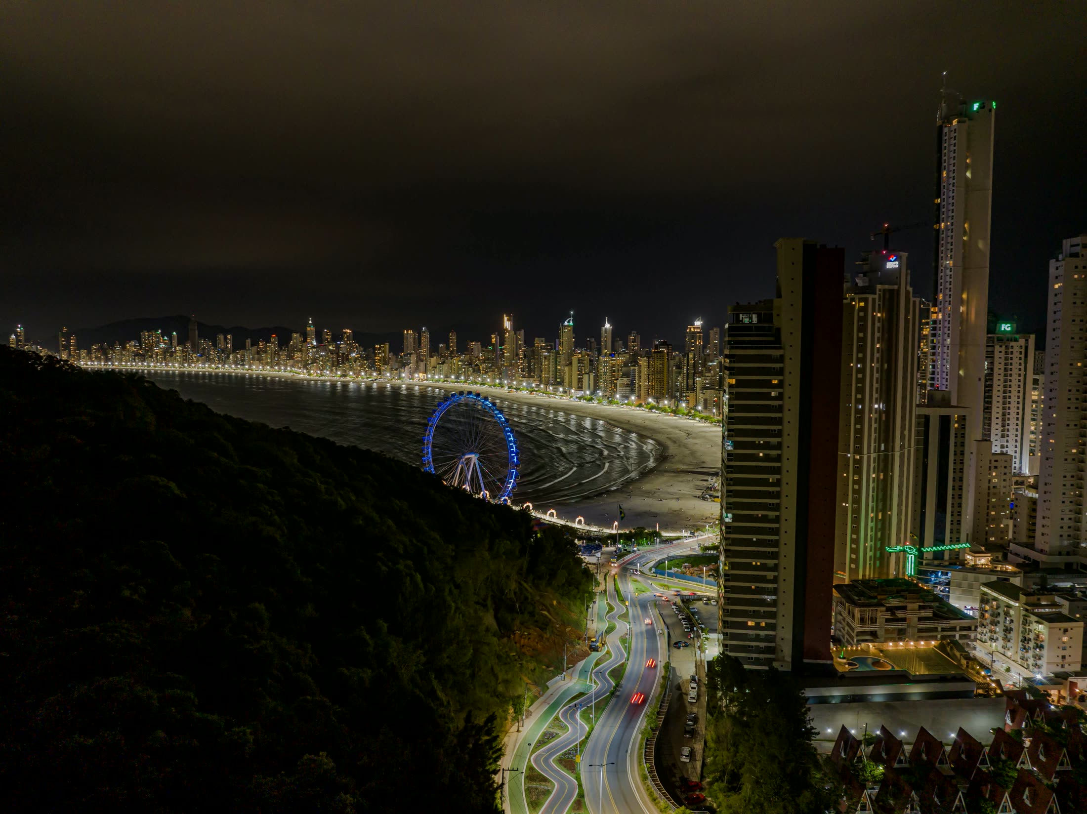 Orla de Balneário Camboriú à noite, prédios iluminados e roda-gigante junto à praia