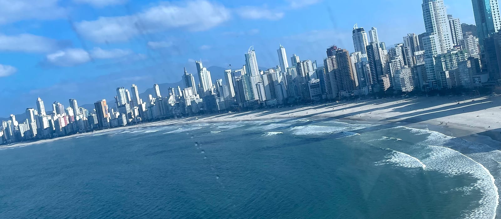 Balneário Camboriú hoje: a Praia Central com a faixa de areia larga e o skyline de arranha-céus acompanhando a orla