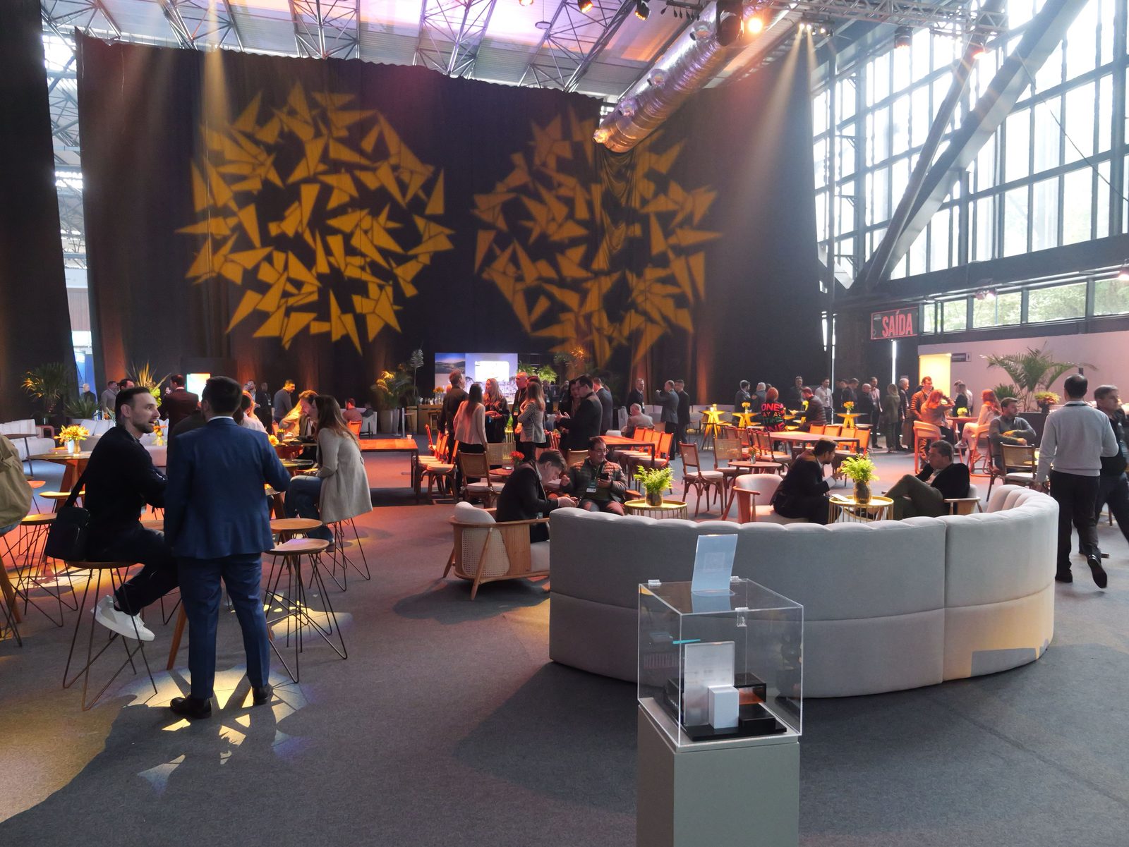 Área de convivência montada dentro do pavilhão do Expocentro, com mesas altas e público circulando