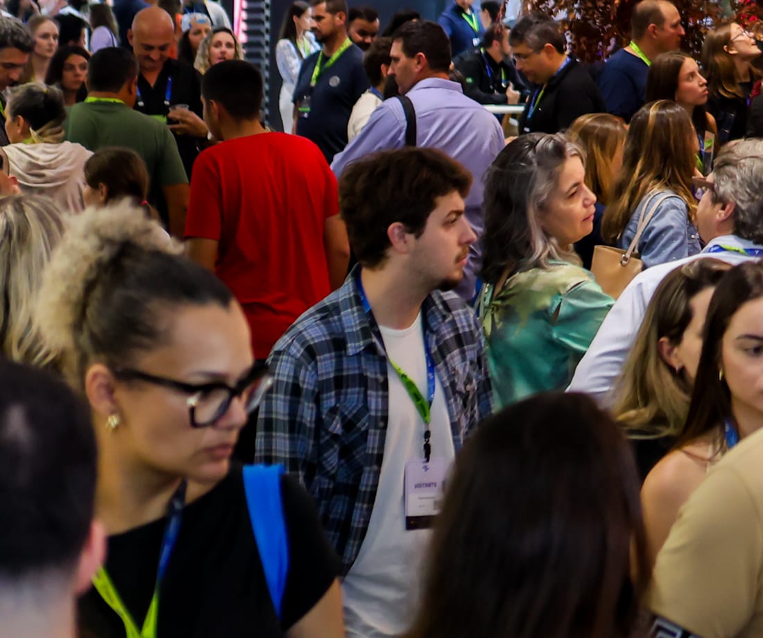 Corredor de estandes lotado de visitantes de crachá durante uma feira no Expocentro