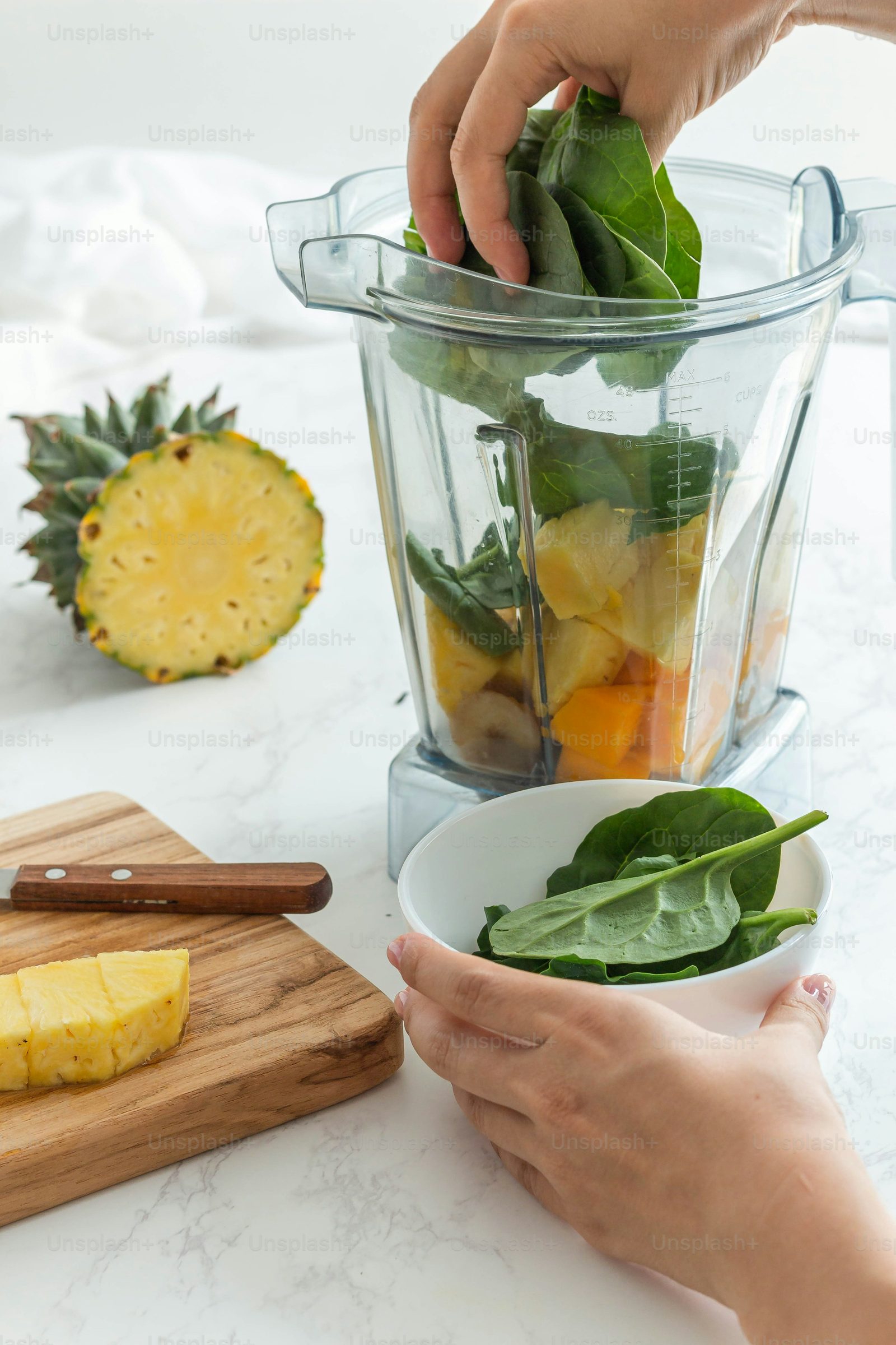 Preparo de smoothie com folhas verdes e frutas frescas sobre a bancada