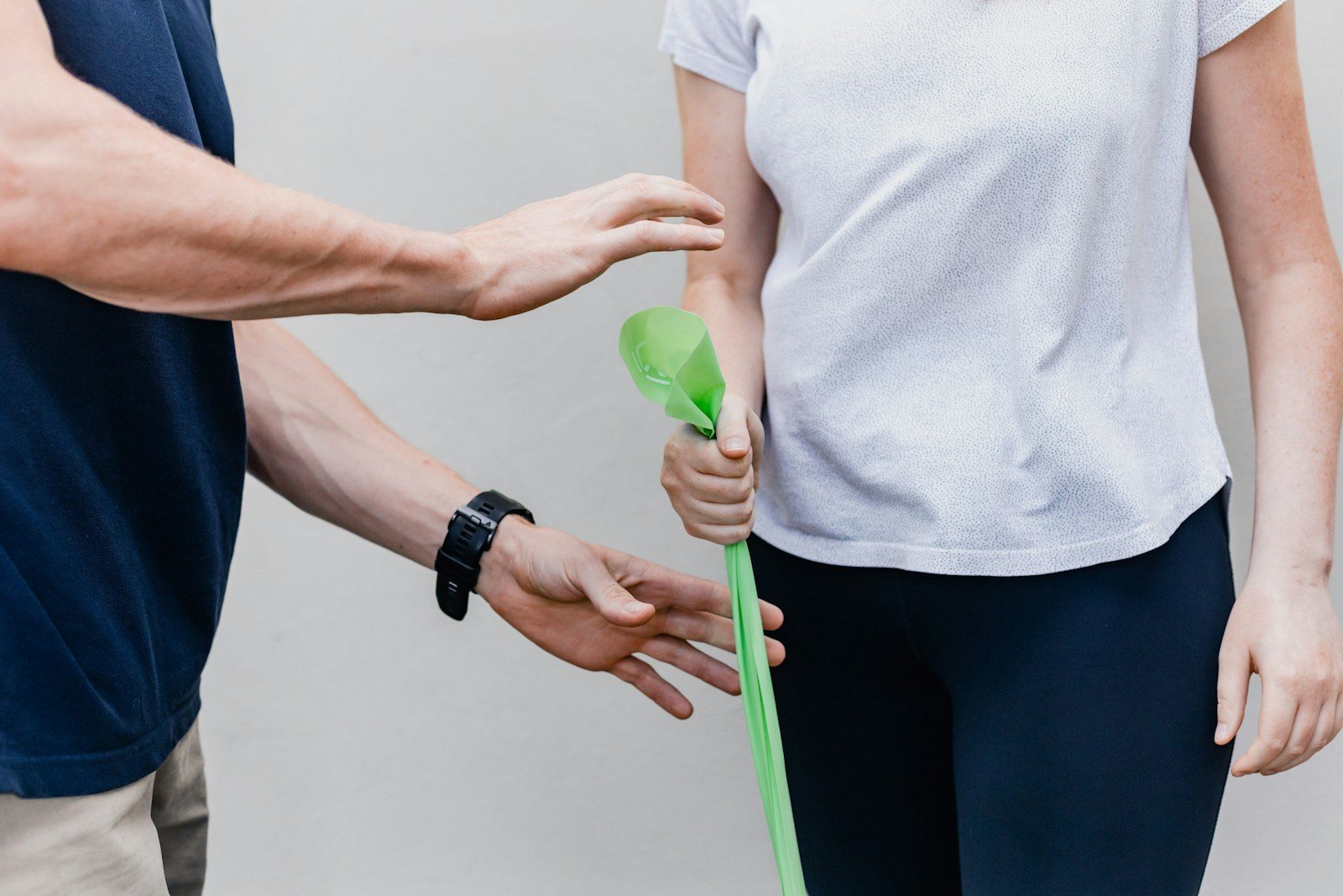 Profissional de saúde auxilia paciente num exercício com faixa elástica verde