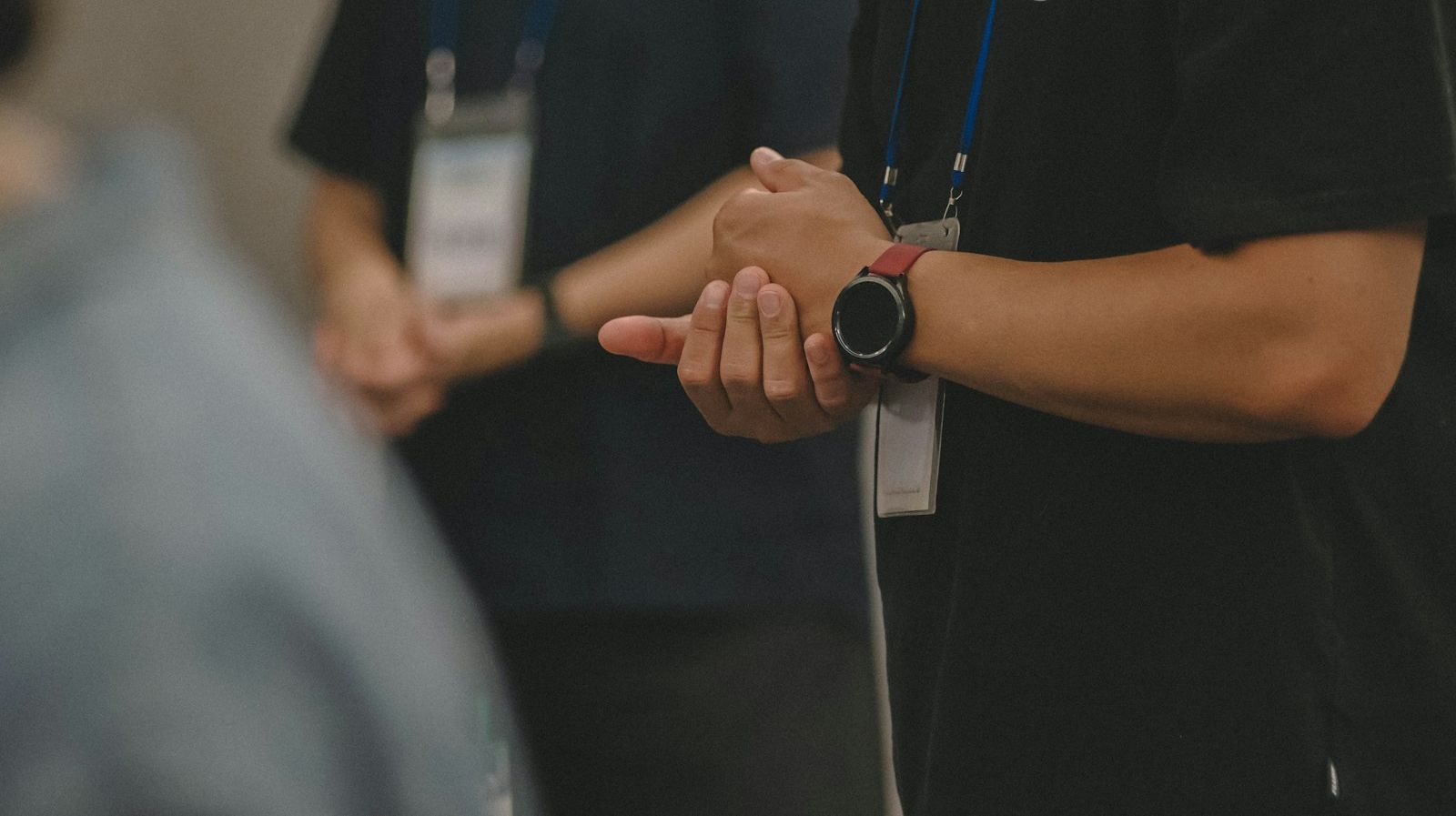 Duas pessoas de roupa de trabalho conversam num corredor de feira, com cordão e crachá de credenciamento no pescoço