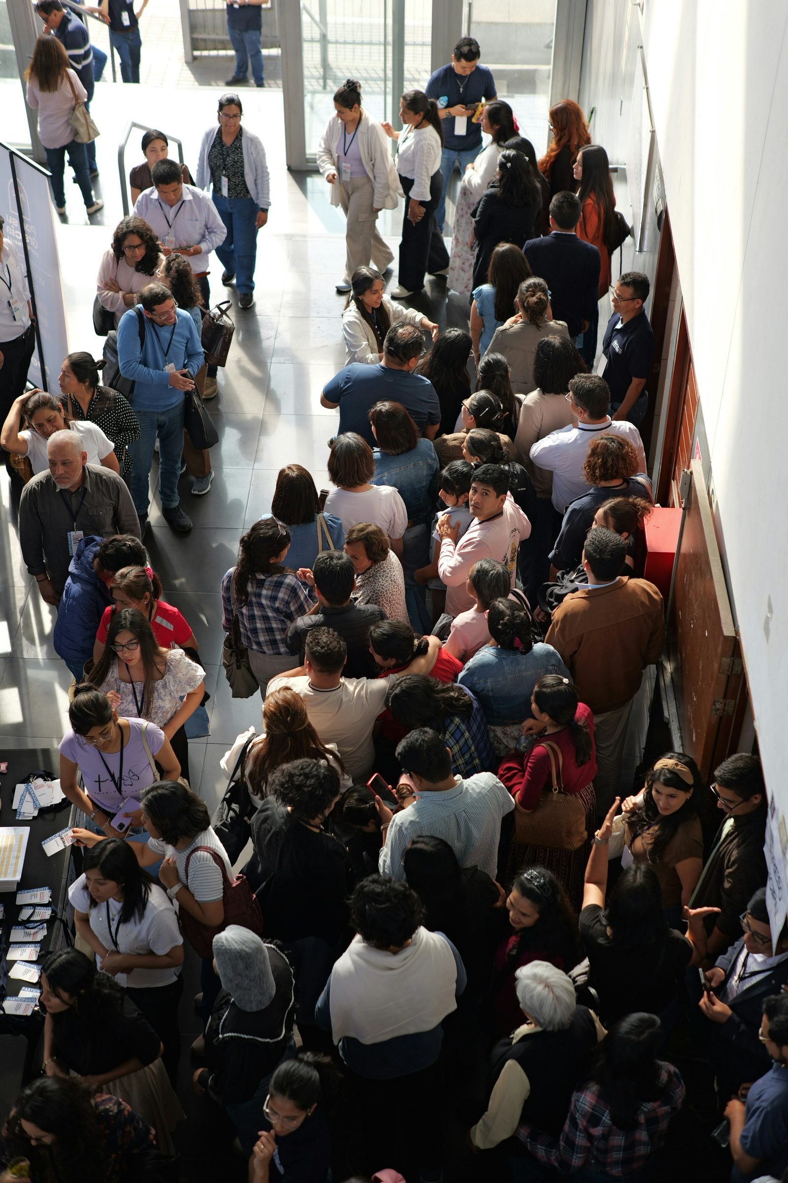 Fila de pessoas com crachá aguardando o credenciamento na entrada de um evento